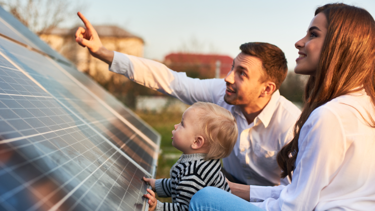 Mother and father with their toddler looking at solar panels on a sunny day